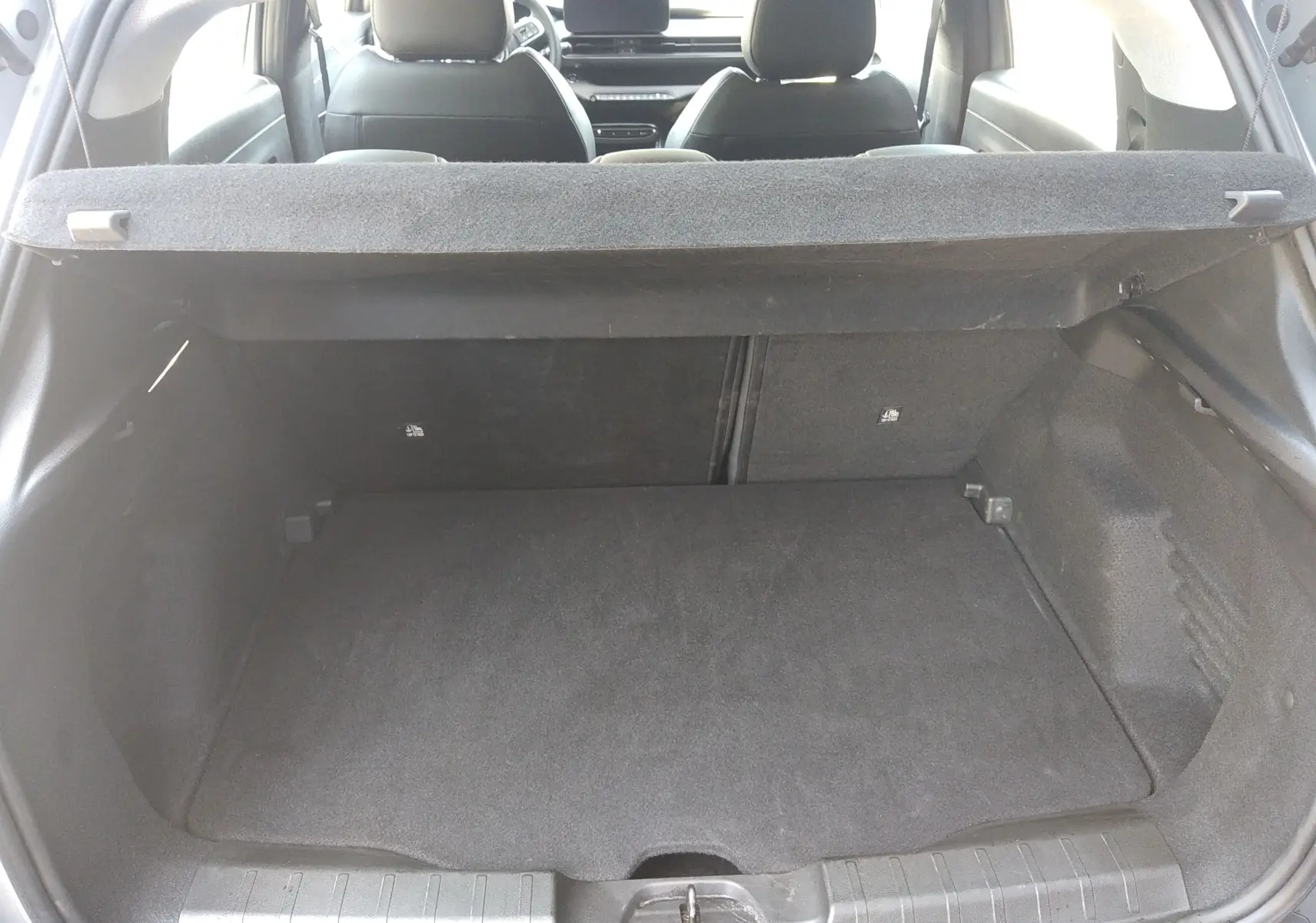 Vue intérieure du coffre spacieux du Jeep Avenger eHYBRID 110ch gris, avec banquette arrière et tablette cache-bagages visibles.