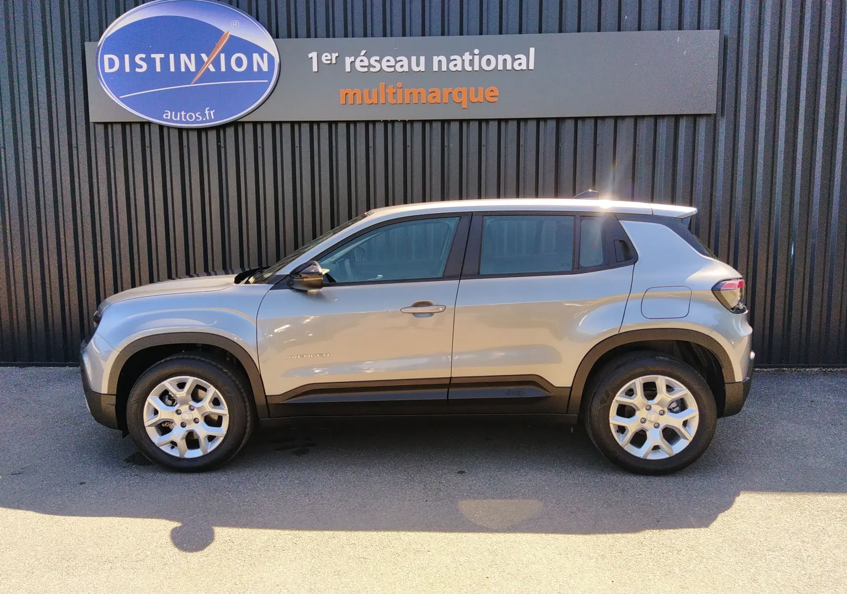 Vue de profil côté gauche d'un Jeep Avenger eHYBRID gris 2025 avec jantes alliage et détails noirs contrastants.