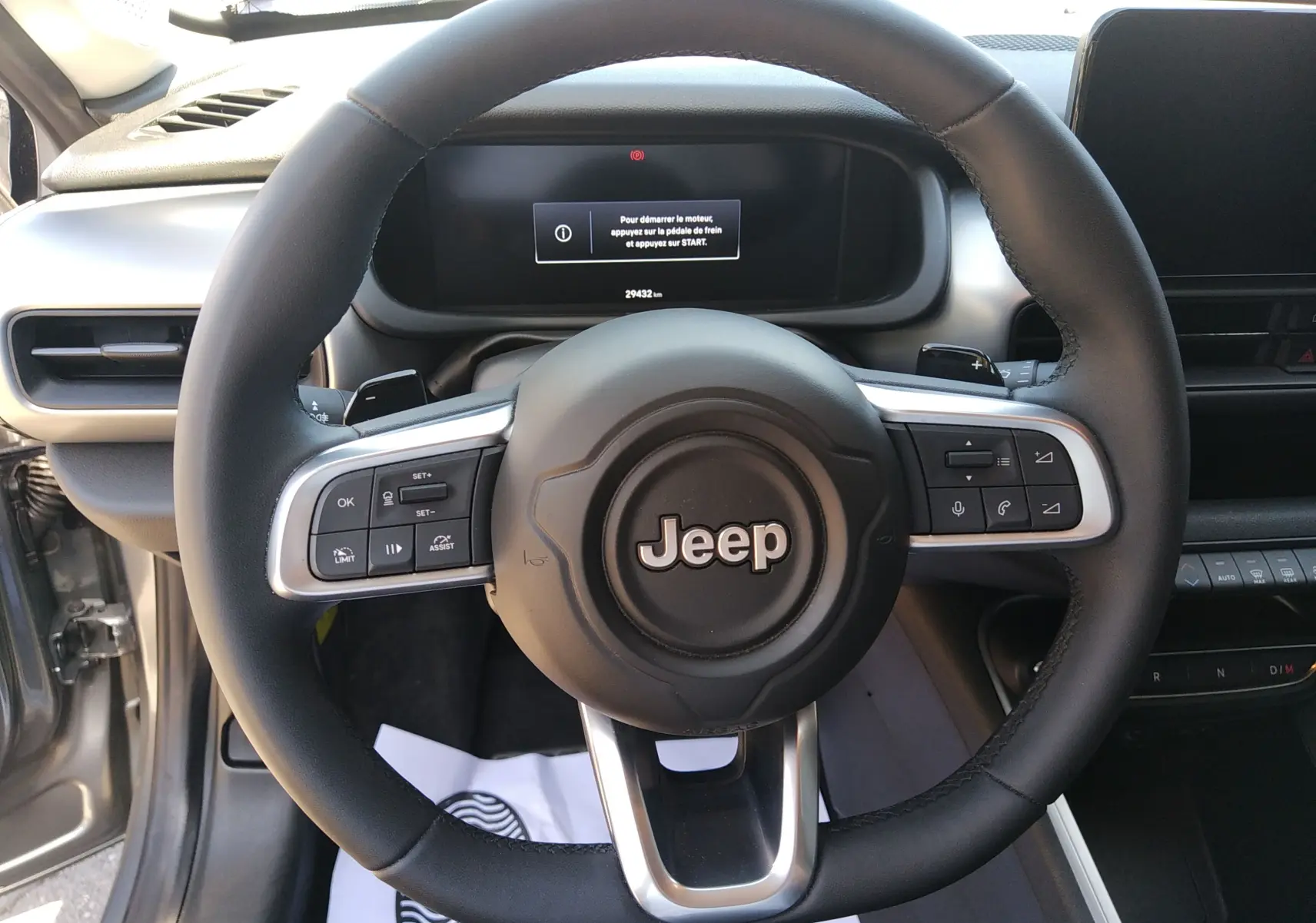 Vue rapprochée du volant noir du Jeep Avenger eHYBRID 2025 avec commandes intégrées et tableau de bord numérique.
