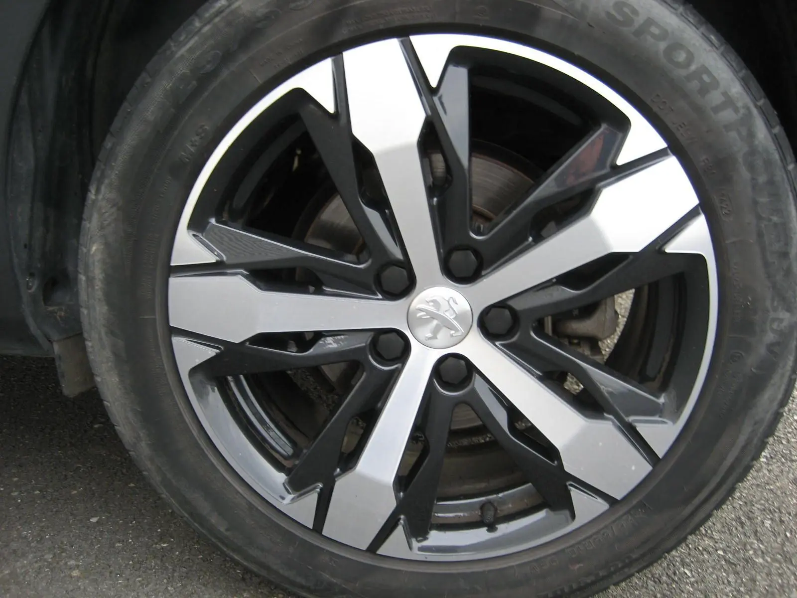 Gros plan sur la jante bicolore noire et argentée du Peugeot 3008 Business 2020 avec logo lion au centre.