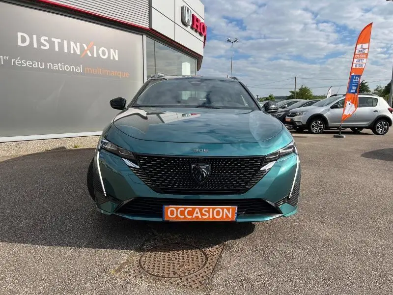 Vue frontale d'une Peugeot 308 SW 2023 en Bleu Avatar avec calandre noire et plaque "OCCASION" orange visible.