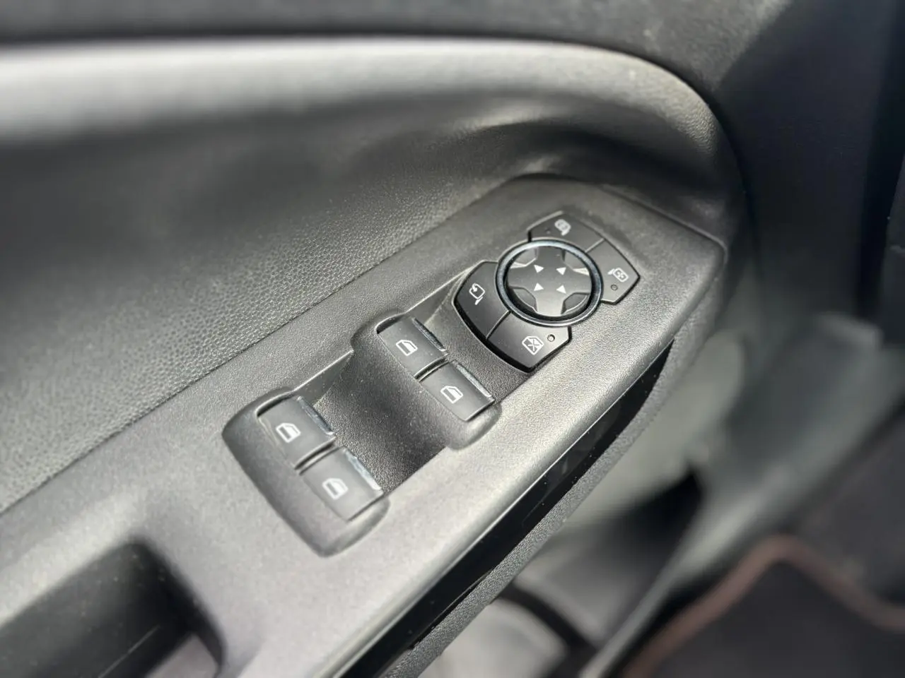 Gros plan sur les commandes des vitres et rétroviseurs côté conducteur d'un Ford EcoSport 2019 noir.