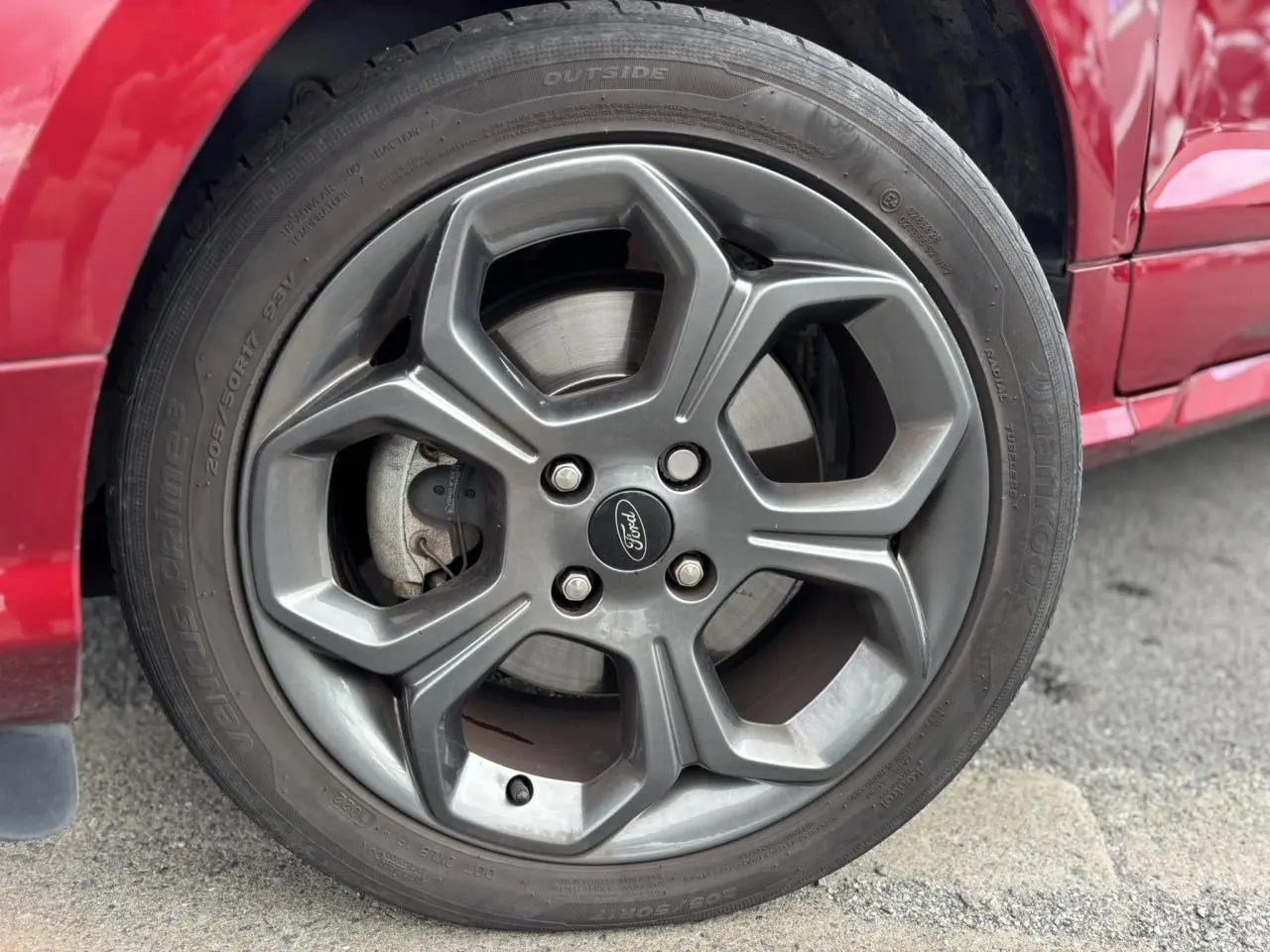 Gros plan sur la roue avant droite d'un Ford EcoSport rouge 2019 avec jante alliage et pneu Hankook.