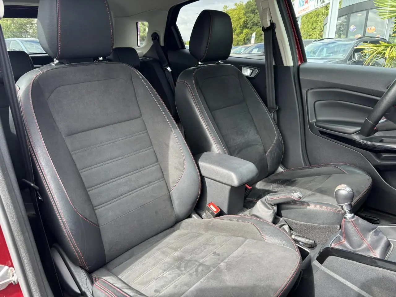 Intérieur avant du Ford EcoSport rouge 2019, sièges cuir/tissu noirs avec surpiqûres rouges et levier de vitesse manuel.