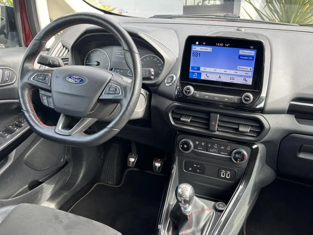 Vue intérieure côté conducteur du Ford EcoSport rouge 2019, volant cuir ST-Line et écran tactile GPS visible.