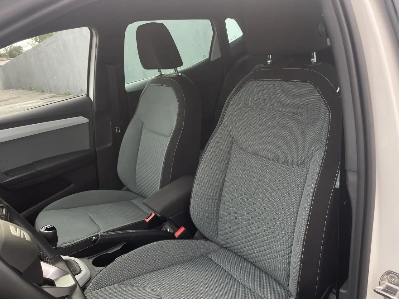 Intérieur de la SEAT IBIZA 2025, vue côté droit sur les sièges avant gris avec coutures blanches et volant multifonction.