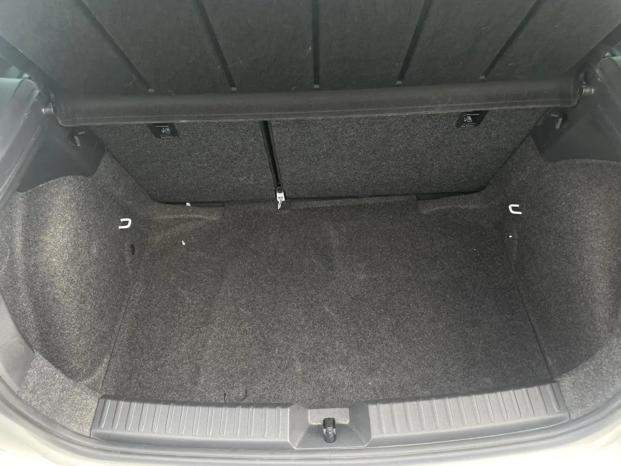 Coffre ouvert de la SEAT Ibiza blanche 2025, montrant un espace de rangement propre et doublé de moquette grise.