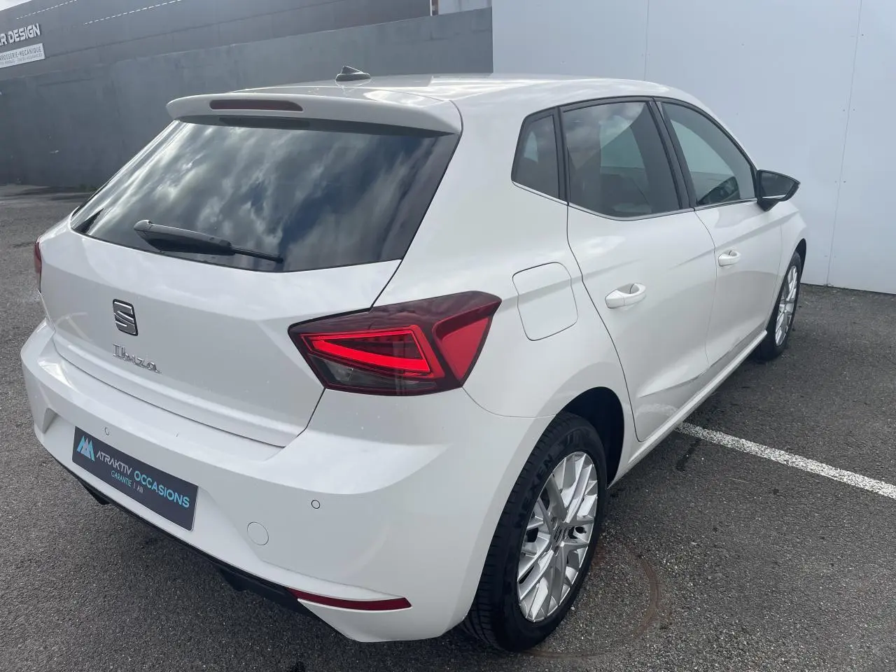 Vue 3/4 arrière droite d'une SEAT Ibiza blanche avec feux arrière LED en triangle et jantes alliage 16 pouces.