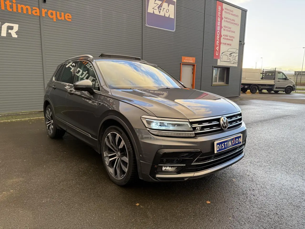 Volkswagen Tiguan gris Indium métallisé en 3/4 avant droit avec jantes alliage et calandre R-Line visible.