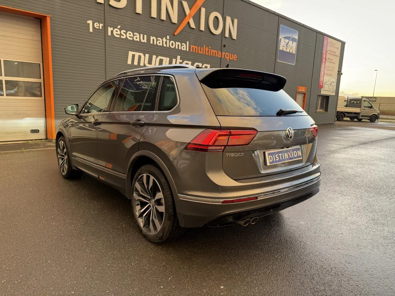 Vue 3/4 arrière droite du Volkswagen Tiguan gris Indium métallisé avec jantes alliage 20 pouces et spoiler R-Line.