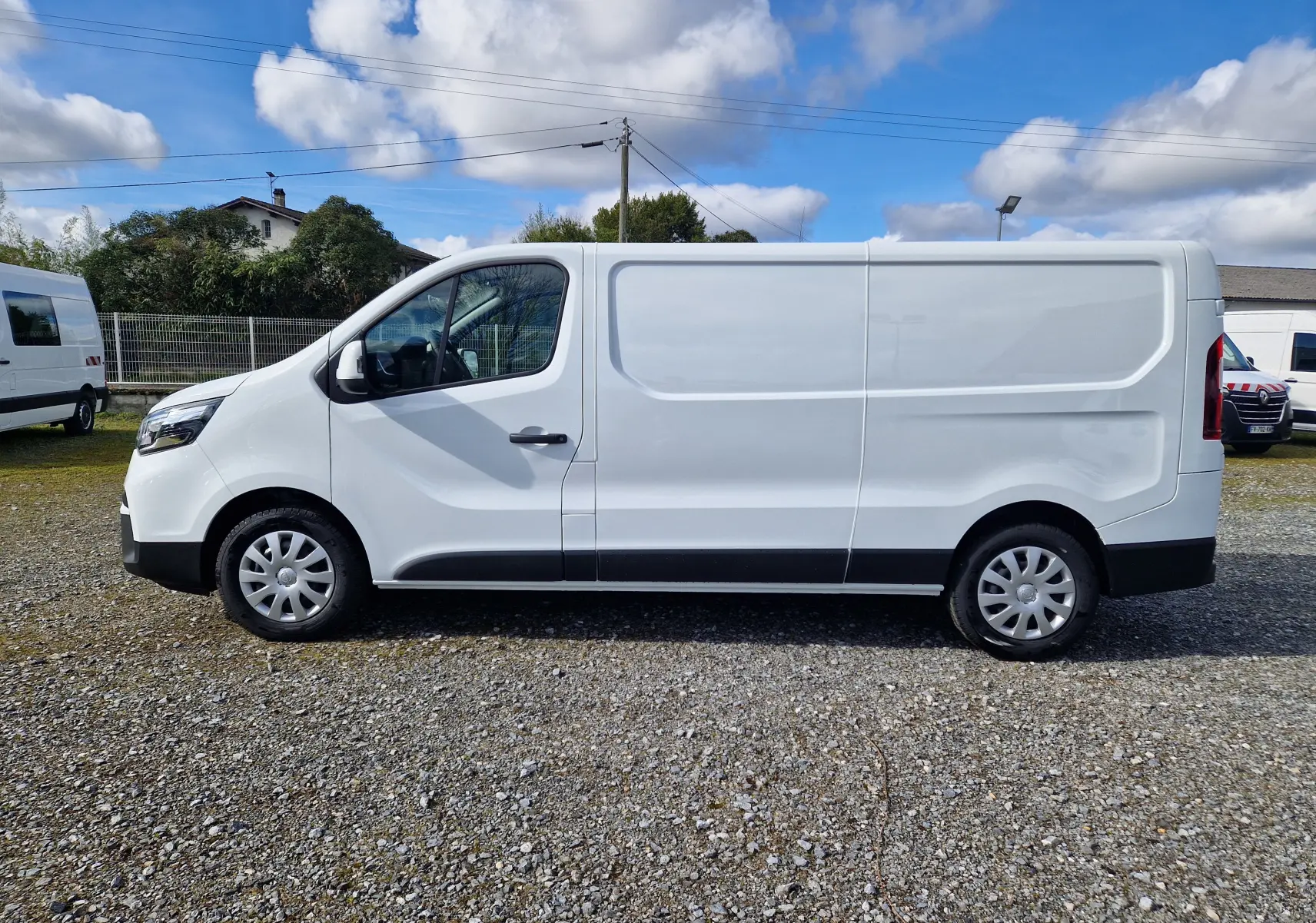 Vue latérale droite d’un utilitaire blanc Nissan Primastar 2025 avec porte coulissante ouverte montrant l’intérieur vide.