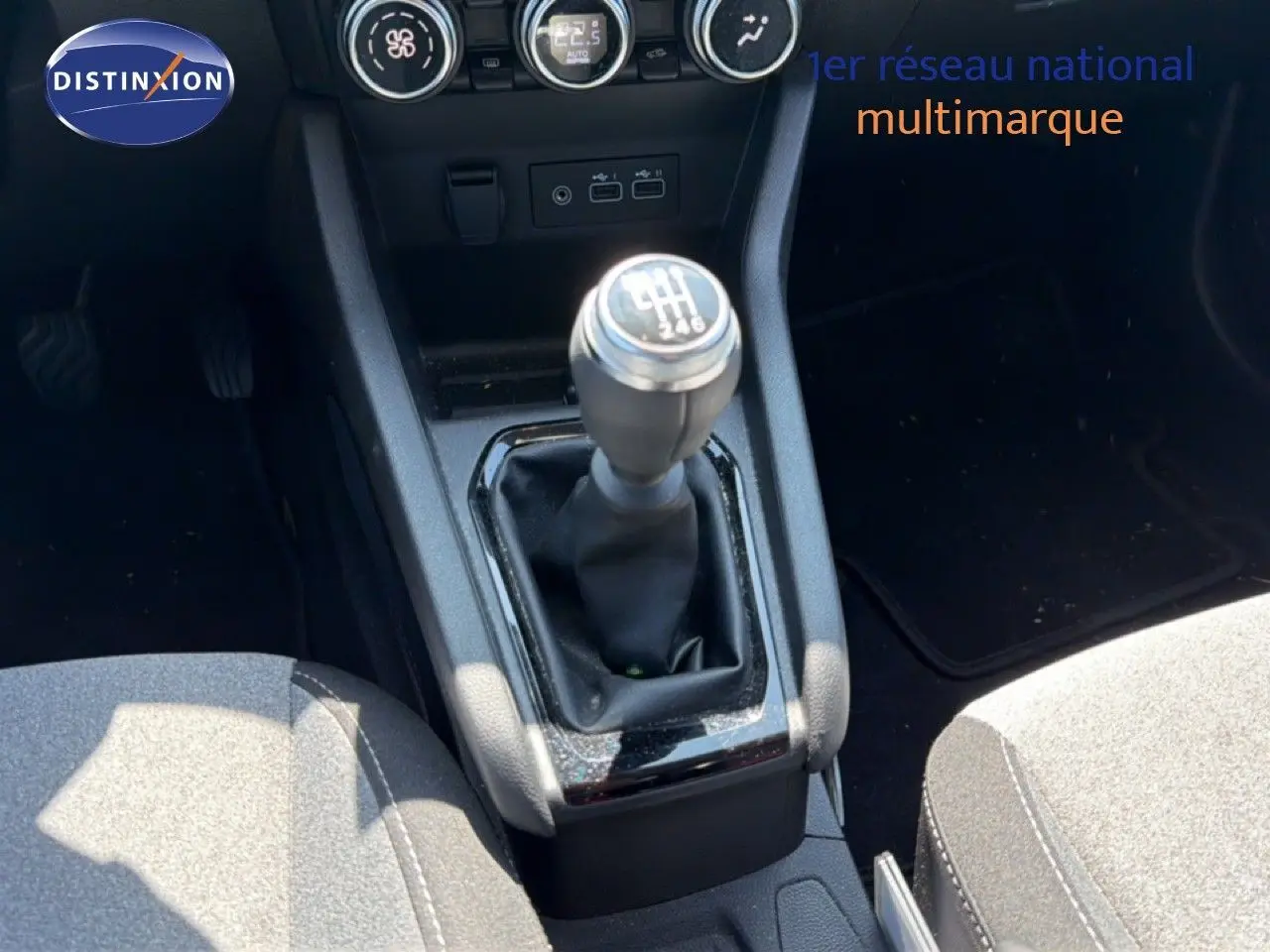 Le levier de vitesse manuel de la Renault Clio V Evolution TCe 90, entouré de la console centrale et des sièges gris.