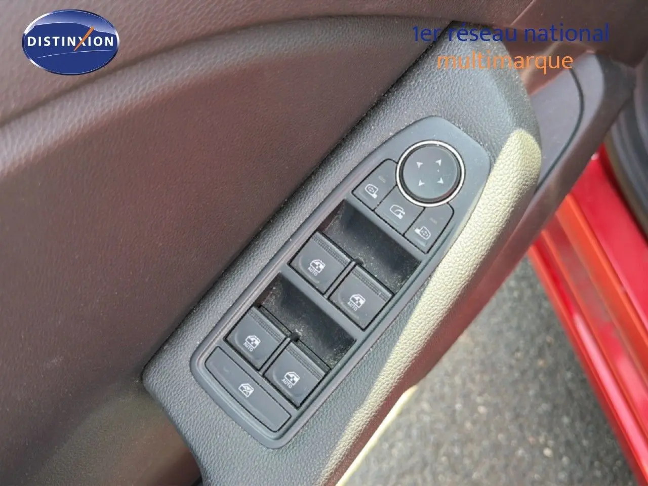 Gros plan sur les commandes des vitres électriques côté conducteur d’une Renault Clio V rouge flamme, porte ouverte.