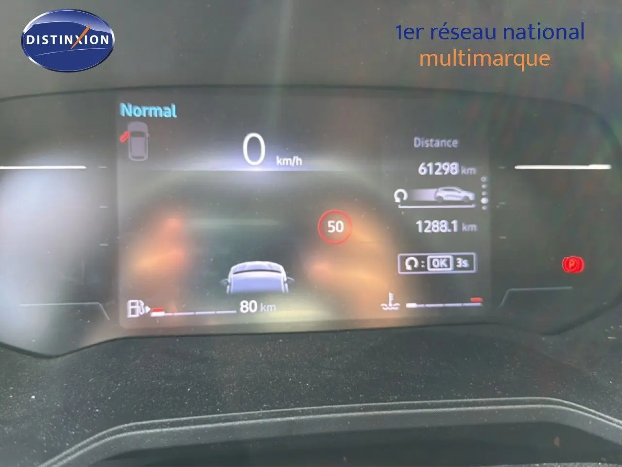 Tableau de bord numérique de Renault Clio V rouge flamme, affichant vitesse, distance et alertes au repos.