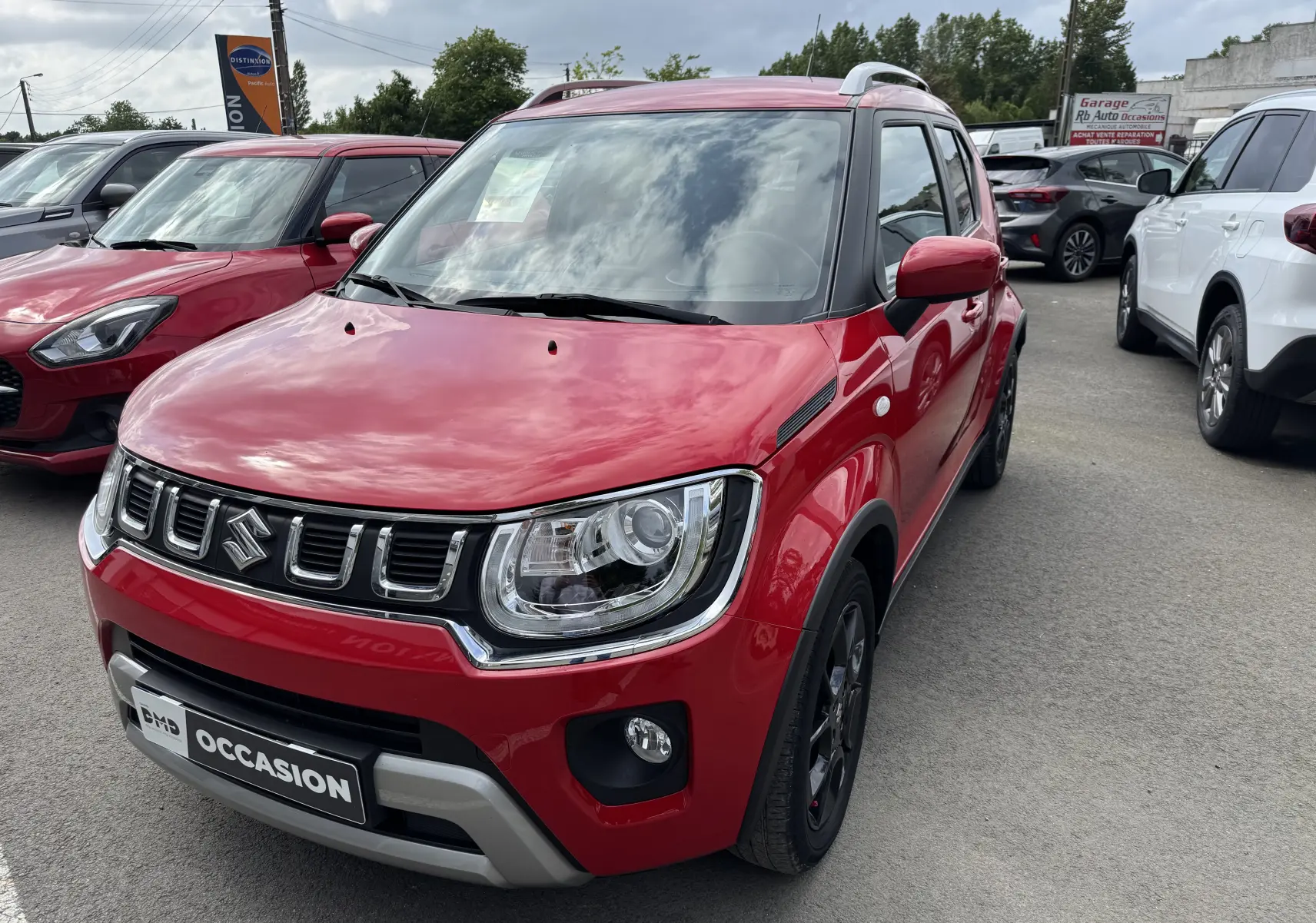 Suzuki Ignis 1.2 Dualjet Hybrid Privilege rouge vue 3/4 avant droit avec calandre chromée et toit blanc.