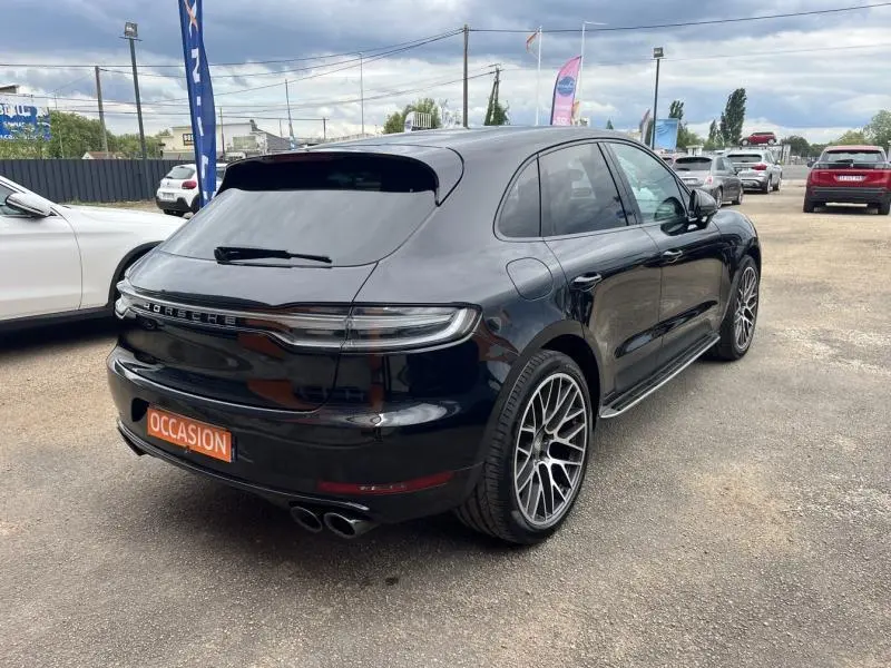 Vue 3/4 arrière droite d'un Porsche Macan noir avec jantes sport et sorties d'échappement doubles noires.