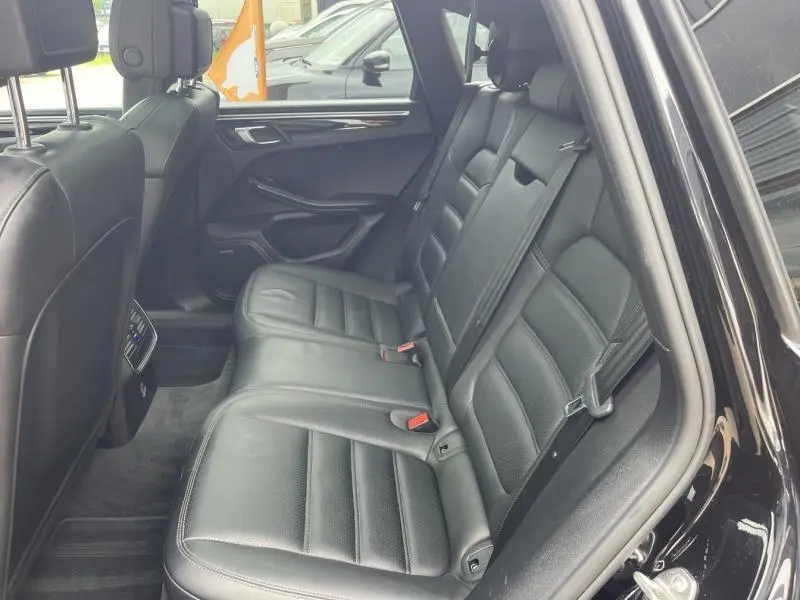 Vue intérieure côté droit des sièges arrière en cuir noir du Porsche Macan 2018 avec ceintures et accoudoir central visible.