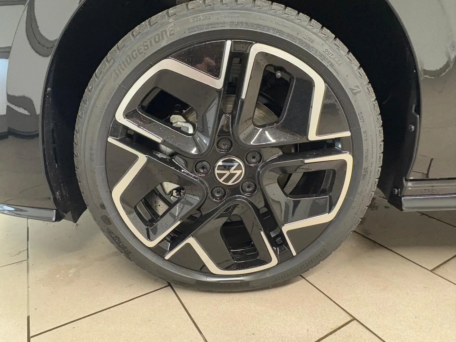 Gros plan sur la roue avant droite noire grenadille de la Volkswagen Golf 2.0 TDI 150 DSG7 R-Line.