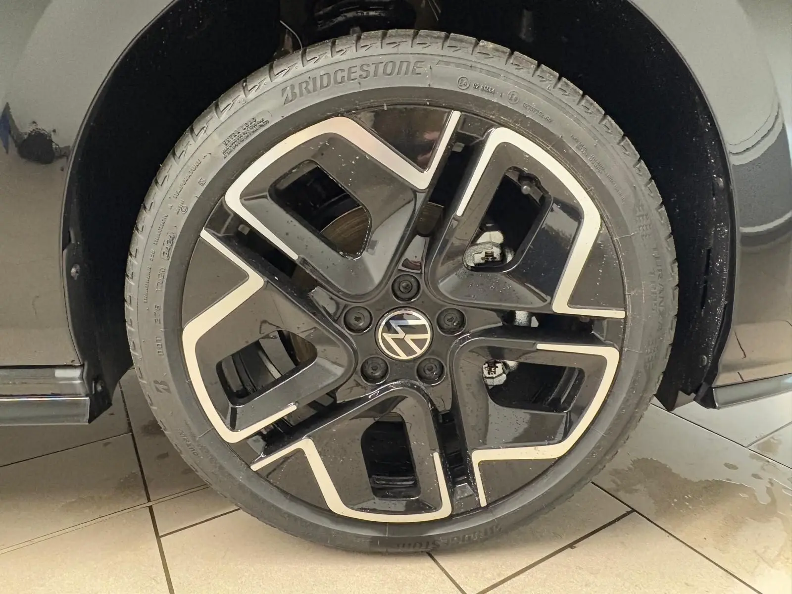 Gros plan sur la roue avant droite noire et argentée d'une Volkswagen Golf 2.0 TDI 150 DSG7 R-Line Noir Grenadille.