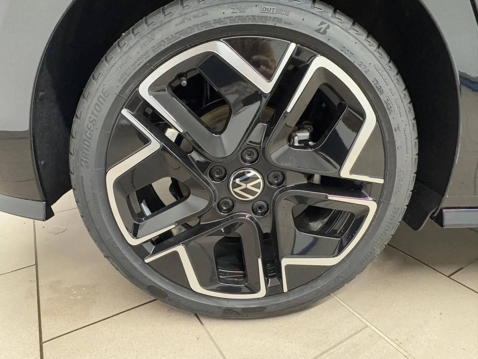 Gros plan sur la roue avant droite d'une Volkswagen Golf 2.0 TDI noire avec jante alliage noir et argent.