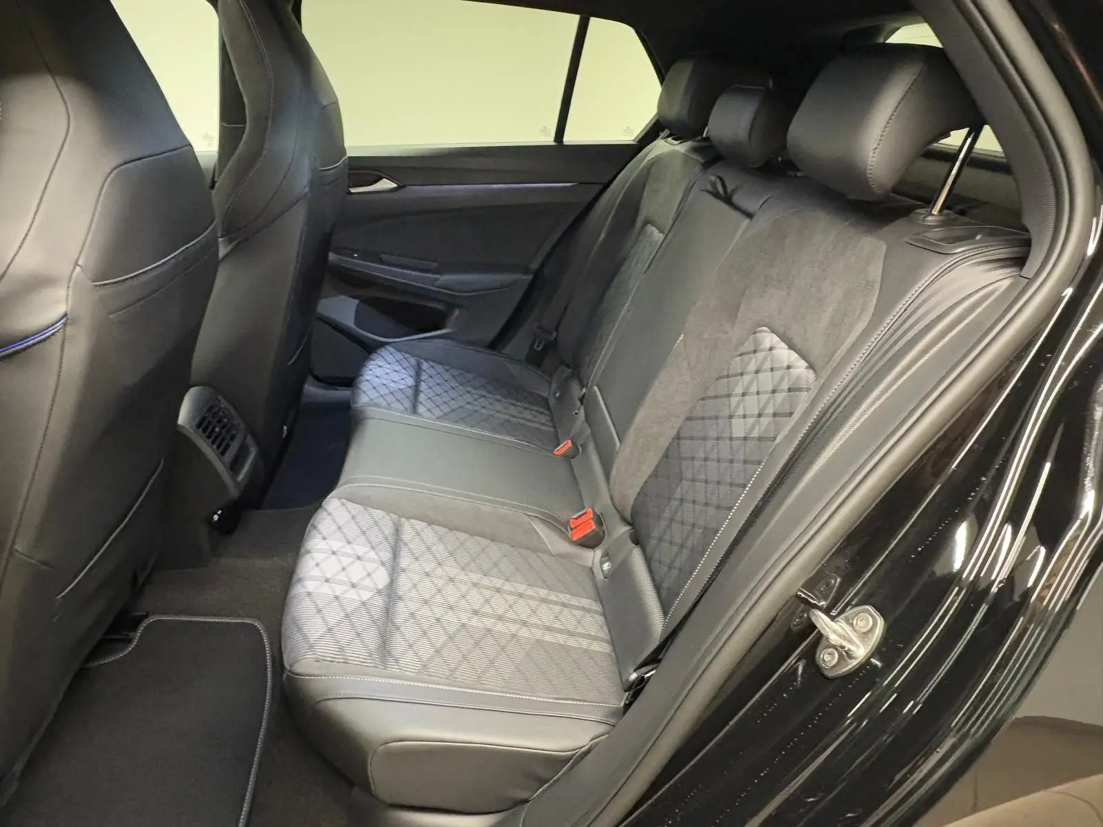 Vue côté droit de l'habitacle arrière de la Volkswagen Golf 2.0 TDI 150 DSG7 R-Line noir grenadille avec sièges en cuir et alcantara.