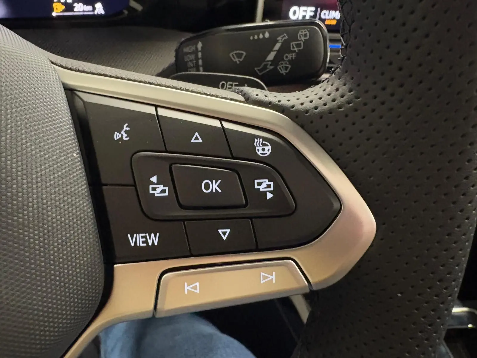 Gros plan sur les commandes multifonctions en cuir perforé du volant chauffant de la Volkswagen Golf 2026 noir Grenadille.