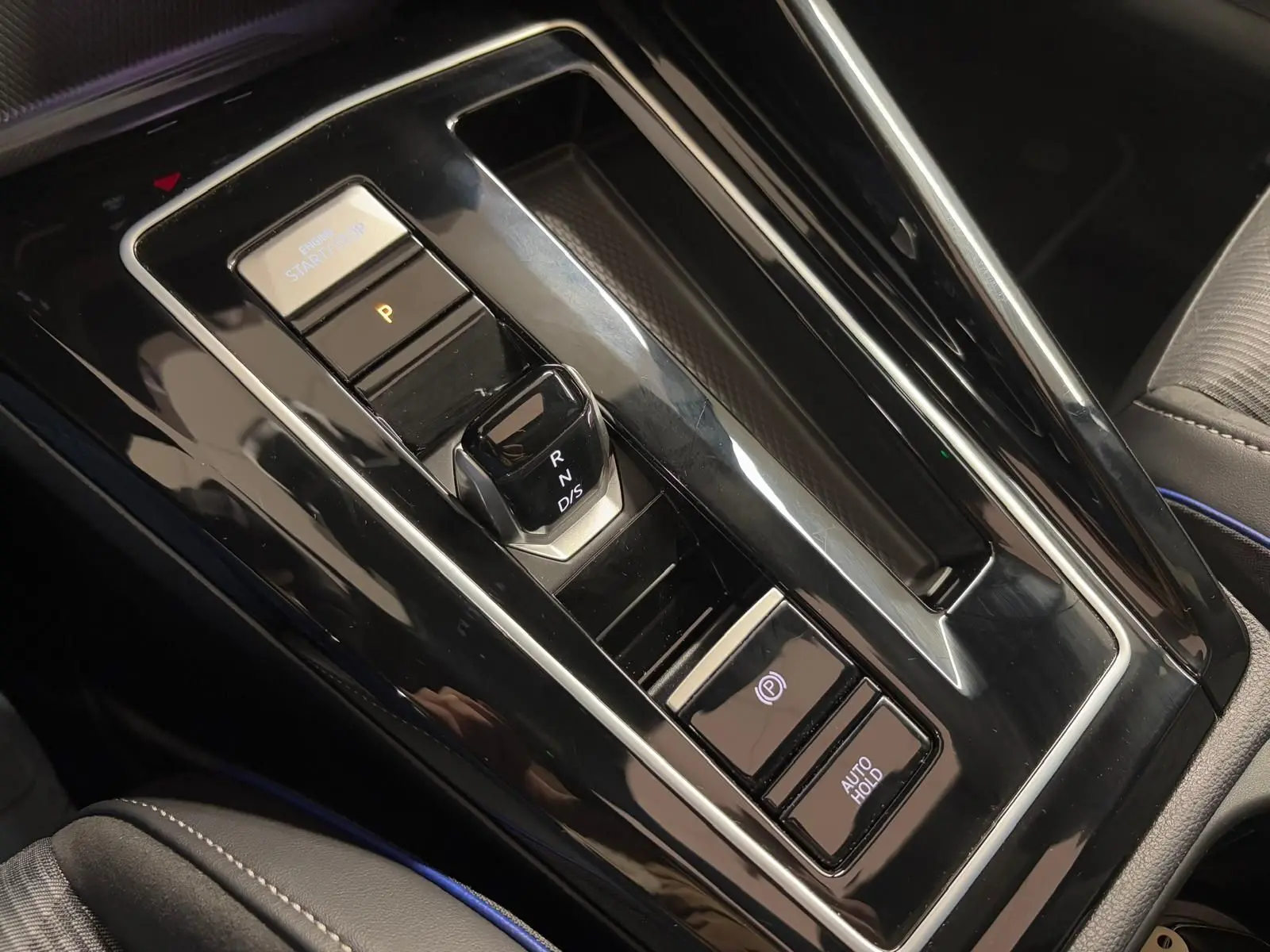 Gros plan sur la console centrale noire brillante de la Volkswagen Golf 2.0 TDI 150 DSG7 R-Line avec levier de vitesses électronique.