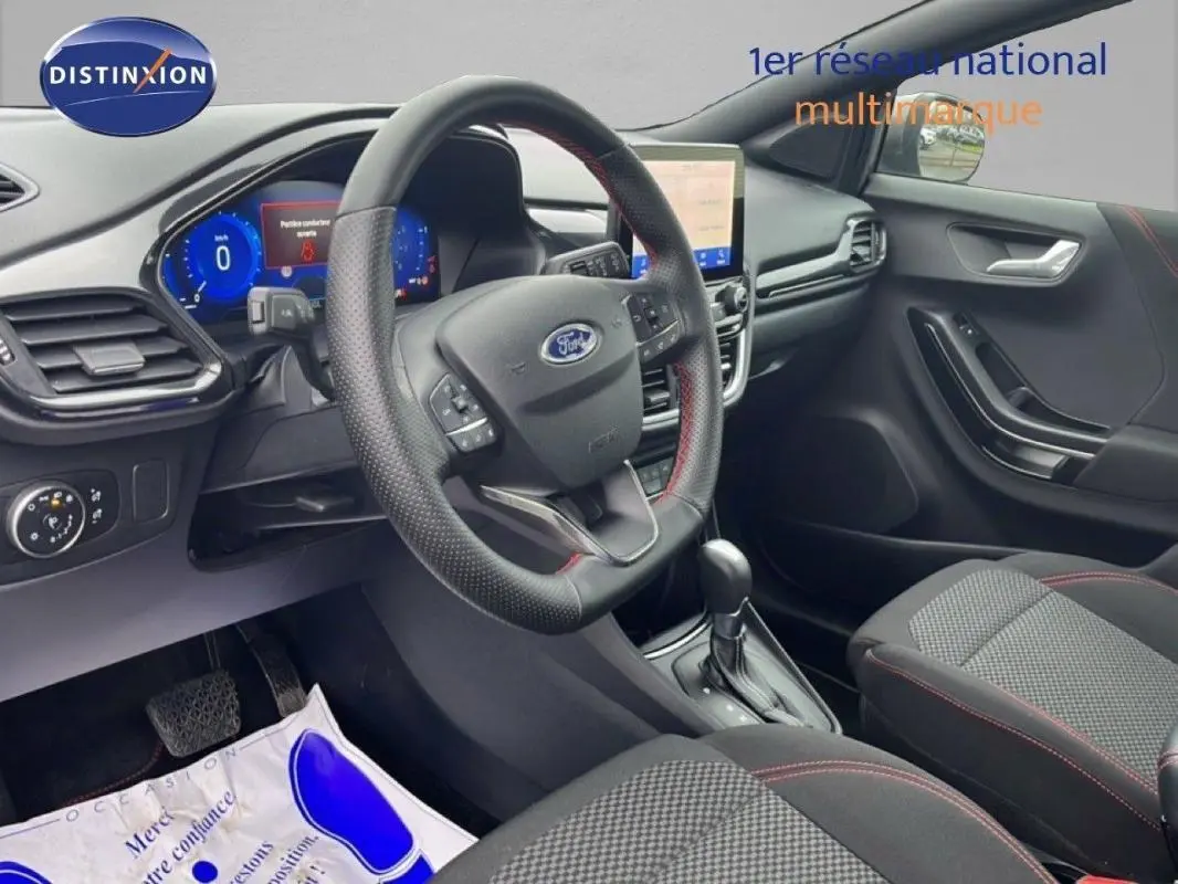 Vue intérieure côté conducteur du Ford Puma gris foncé 2024, avec volant multifonction et écran tactile central.