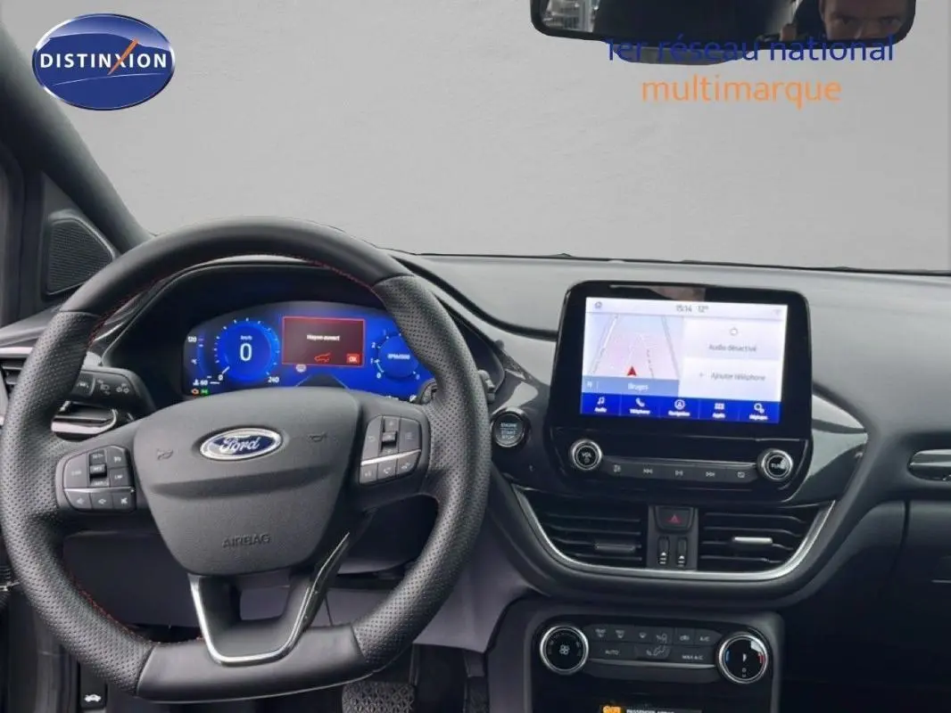 Vue intérieure frontale du tableau de bord du Ford Puma gris foncé 2024 avec écran tactile et volant multifonction.