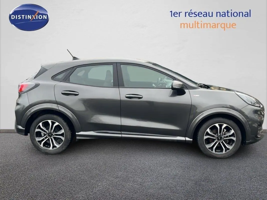 Vue de profil côté gauche d’un Ford Puma gris foncé avec jantes alliage 17 pouces sur fond neutre.