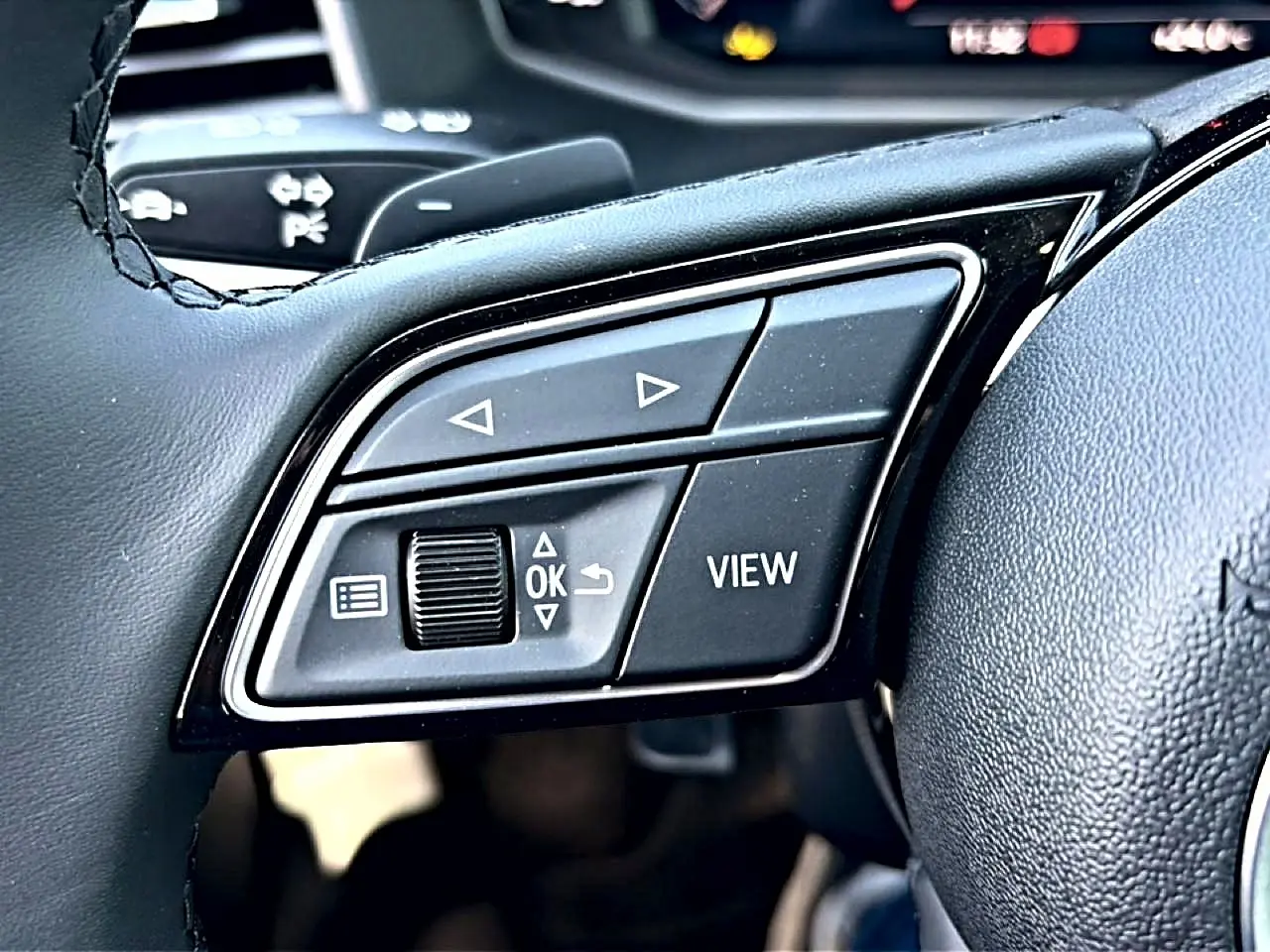 Gros plan sur les commandes multifonctions noires à gauche du volant cuir d’un Audi A1 Sportback 30 TFSI 2026.