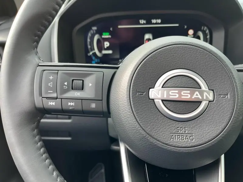 Gros plan sur le volant cuir noir du Nissan Qashqai e-POWER 2024 avec commandes multifonctions et tableau de bord digital.
