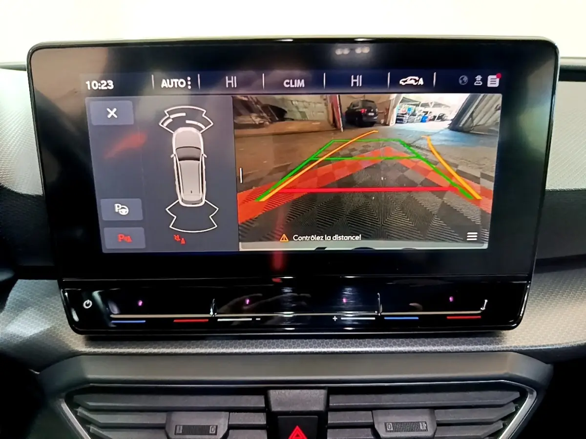 Écran tactile central affichant la caméra de recul et l'aide au stationnement sur une SEAT Leon gris clair, vue intérieure.