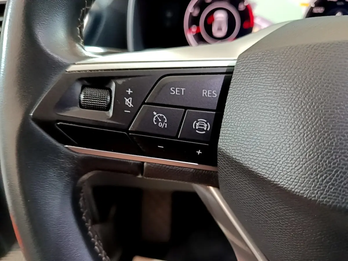 Gros plan sur les commandes du volant cuir de la SEAT LEON 2.0 TDI 150 DSG, avec régulateur de vitesse et aides à la conduite.