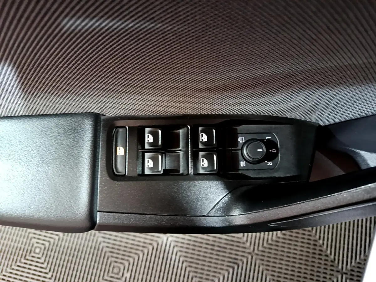 Vue rapprochée du panneau de commandes des vitres et rétroviseurs côté conducteur d'une SEAT Leon gris clair 2022.