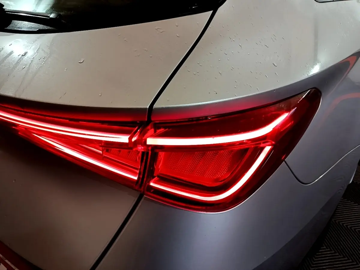 Gros plan sur le feu arrière droit rouge allumé d'une SEAT LEON gris clair 2022 sous pluie légère