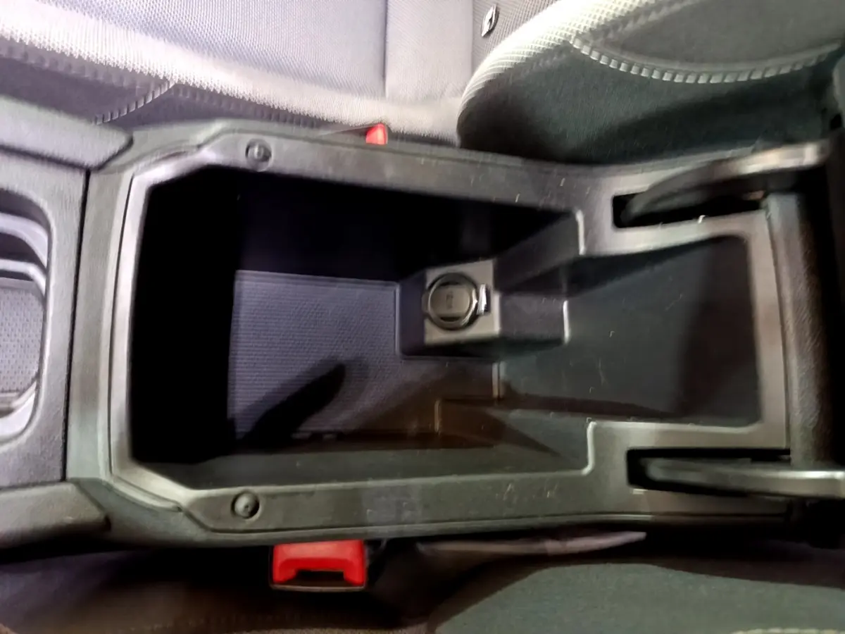 Vide-poche central noir avec prise 12V visible dans l'habitacle d'une SEAT LEON gris clair, vue de dessus rapprochée.