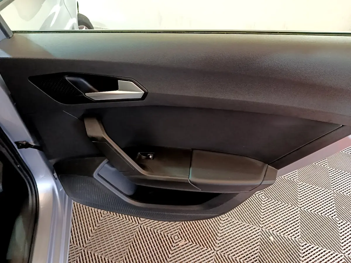 Porte intérieure côté gauche de la SEAT LEON gris clair 2022, avec poignée argentée et accoudoir noir.