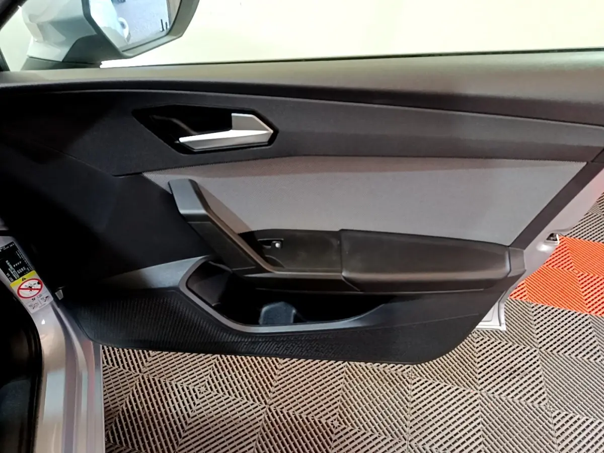 Porte intérieure côté conducteur gris clair de la SEAT LEON 2022 avec poignée argentée et rangement intégré.