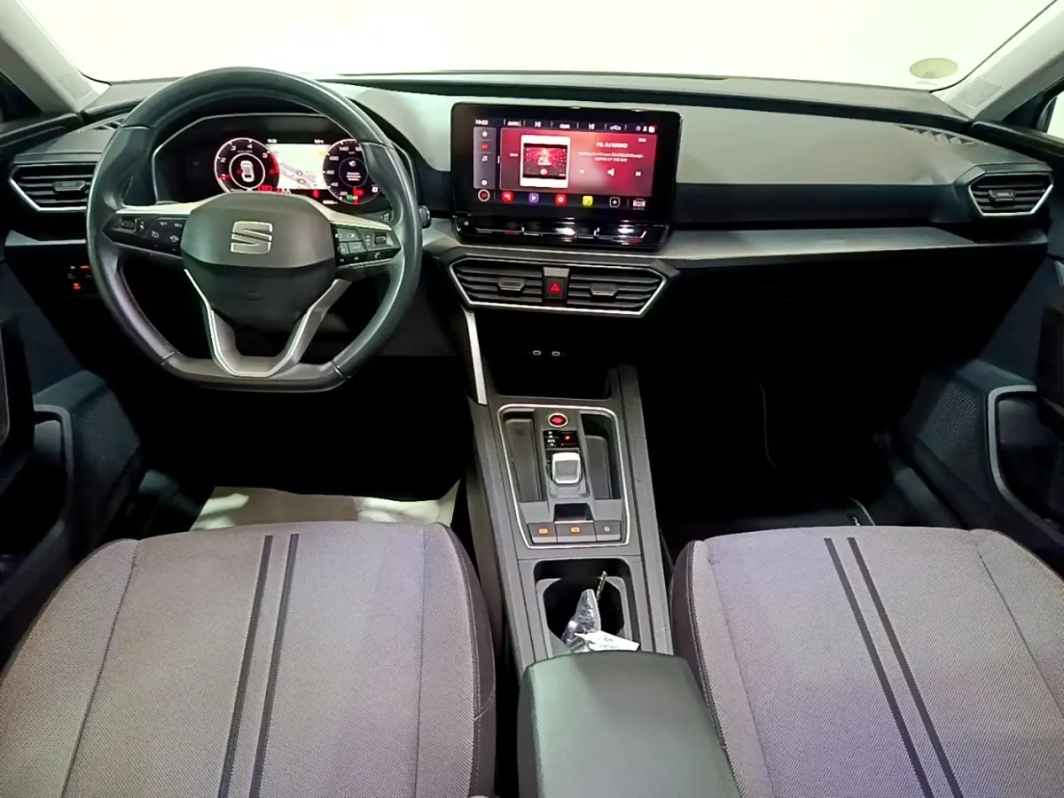 Intérieur de la SEAT LEON 2.0 TDI 2022 vu de face, tableau de bord noir avec écran tactile central et sièges gris.