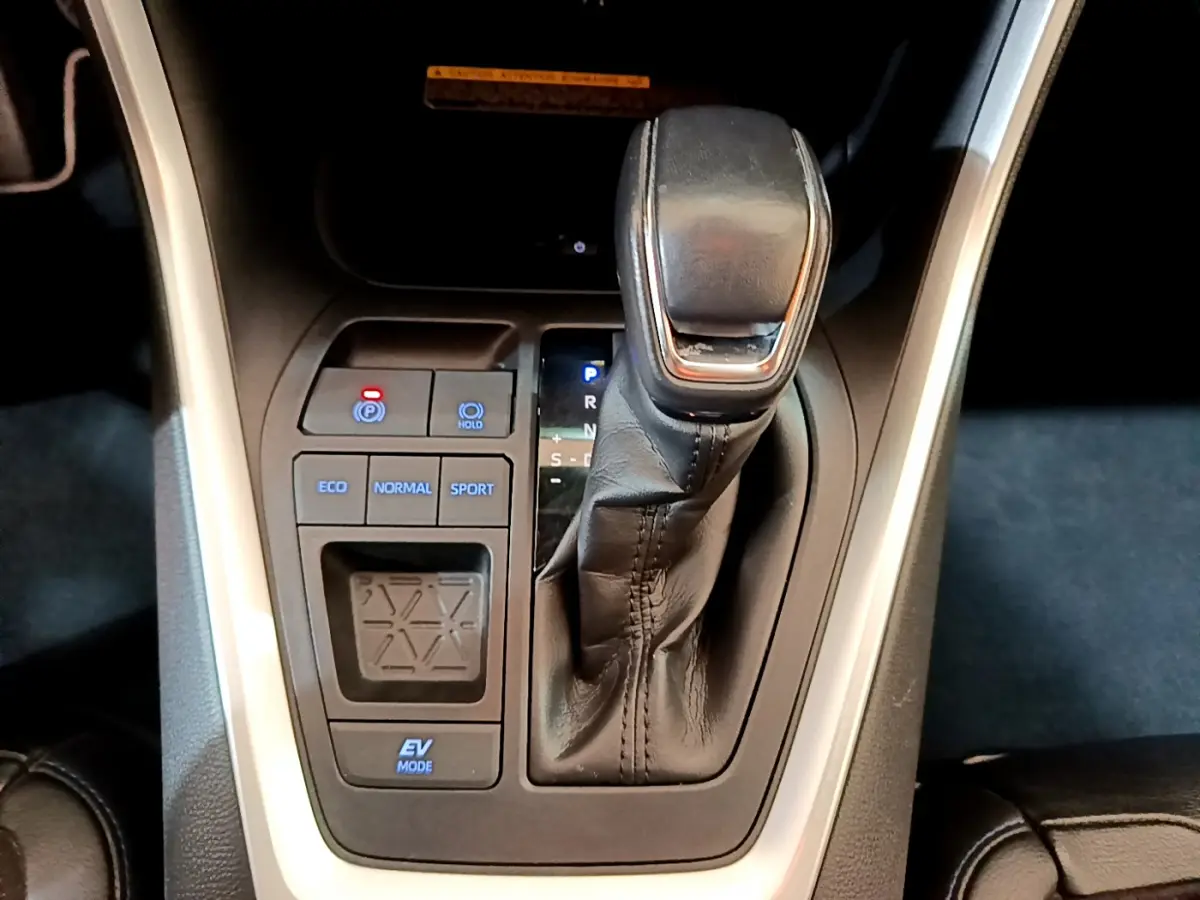 Le levier de vitesses automatique noir du Toyota RAV4 2WD 218ch Collection, vu de dessus, avec boutons de modes de conduite.