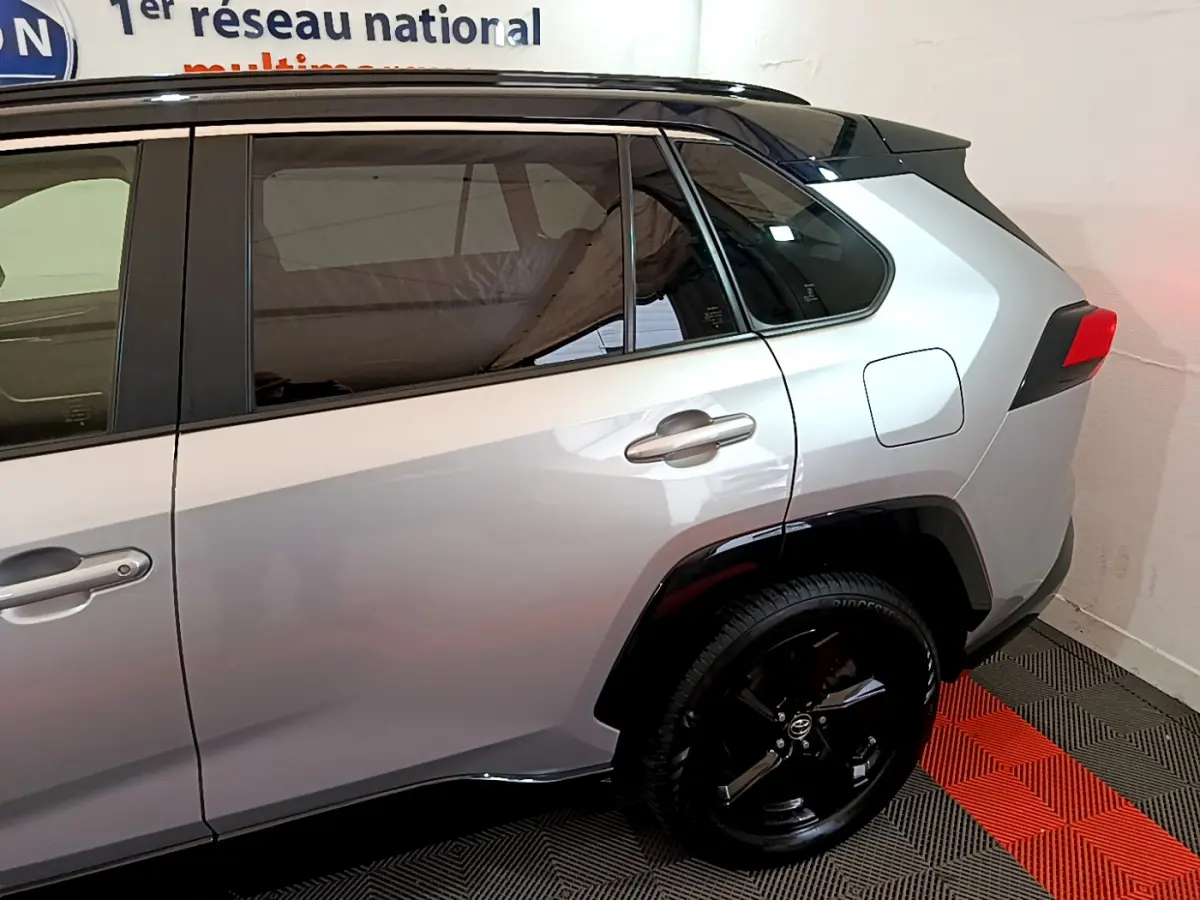 Vue latérale côté droit du Toyota RAV4 gris clair avec jantes noires et vitres teintées.