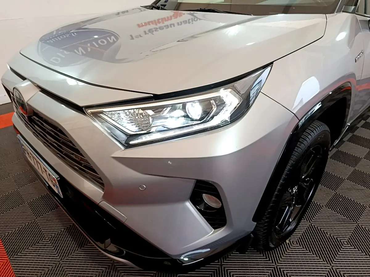 Gros plan sur l'avant droit du Toyota RAV4 gris clair 2019 avec phares LED allumés et jantes noires.
