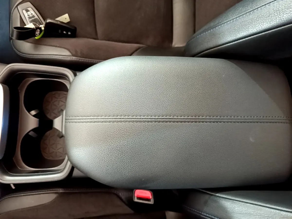Vue rapprochée de l'accoudoir central en cuir noir et porte-gobelets du Toyota RAV4 gris clair 2WD 2019.