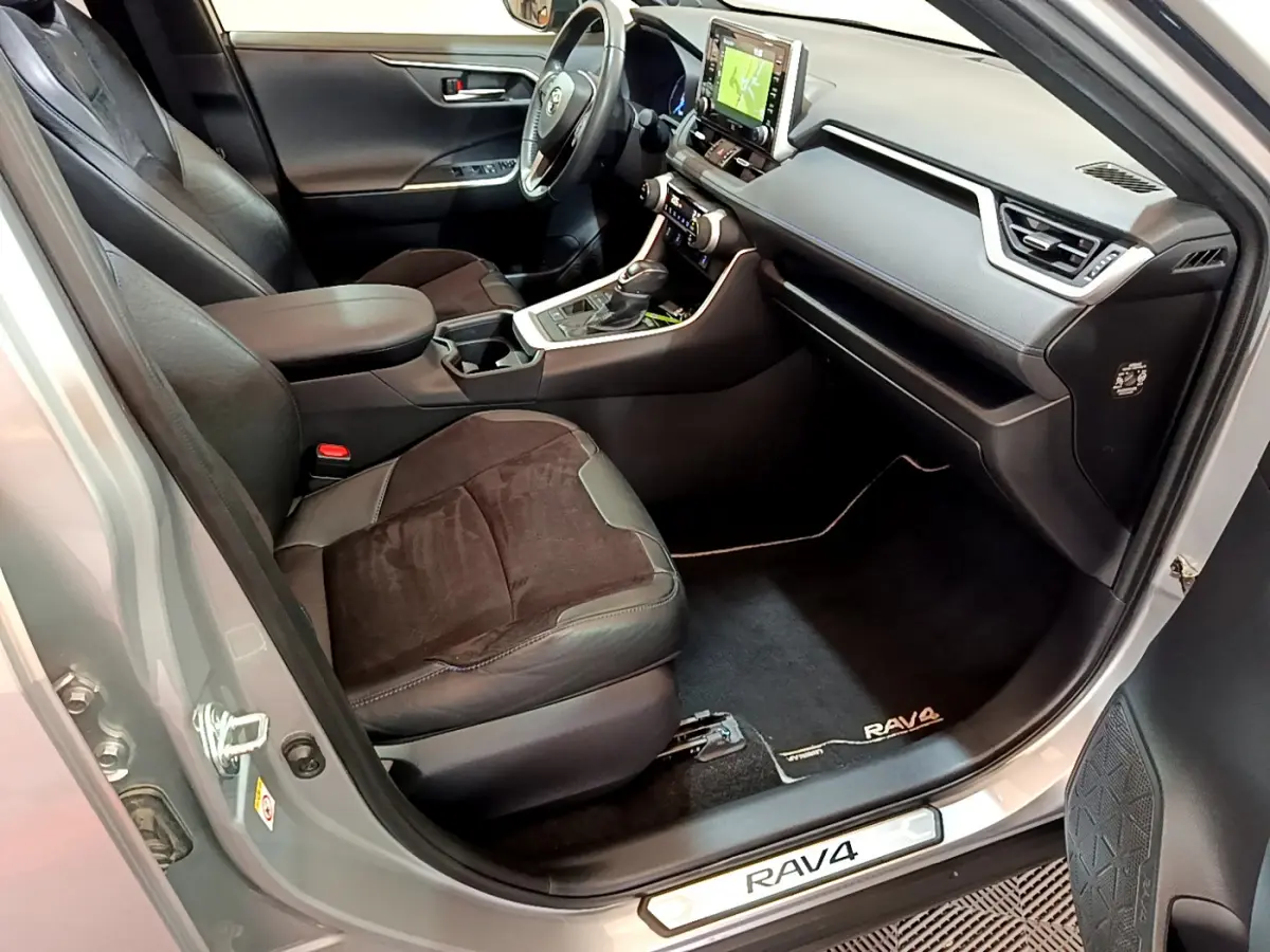 Intérieur avant droit du Toyota RAV4 gris clair 2019, sièges cuir et alcantara, tableau de bord avec écran tactile visible.