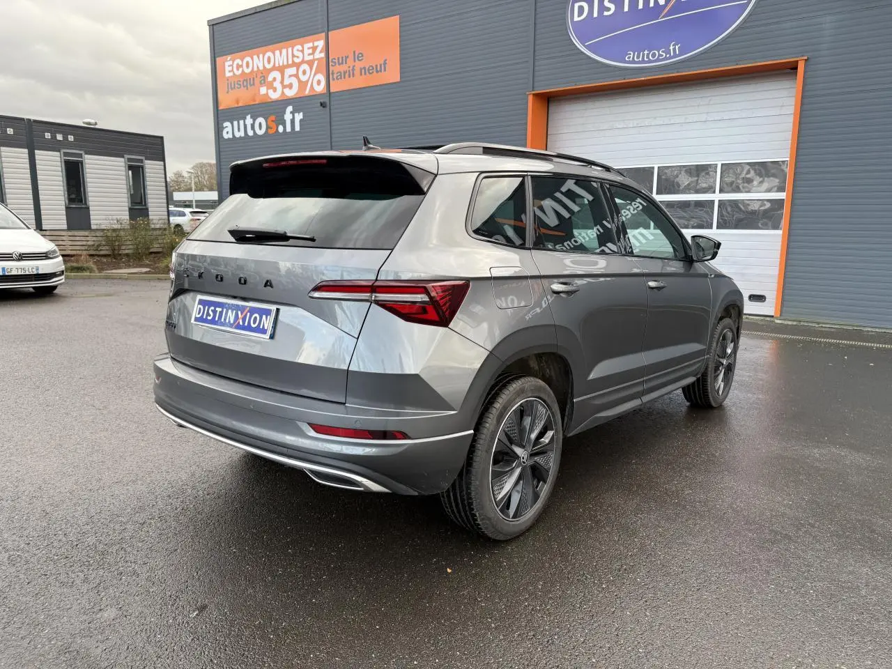 Vue 3/4 arrière droite d'un SKODA KAROQ gris graphite métallisé avec jantes alliage noires et toit ouvrant panoramique.