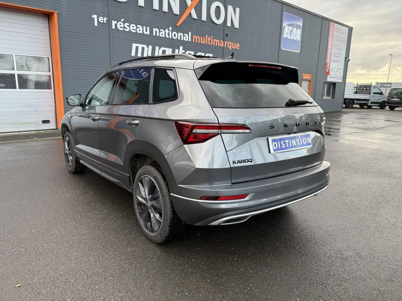 Vue 3/4 arrière droite d'un Skoda Karoq gris graphite métallisé avec jantes alliage noires et toit ouvrant panoramique électrique.