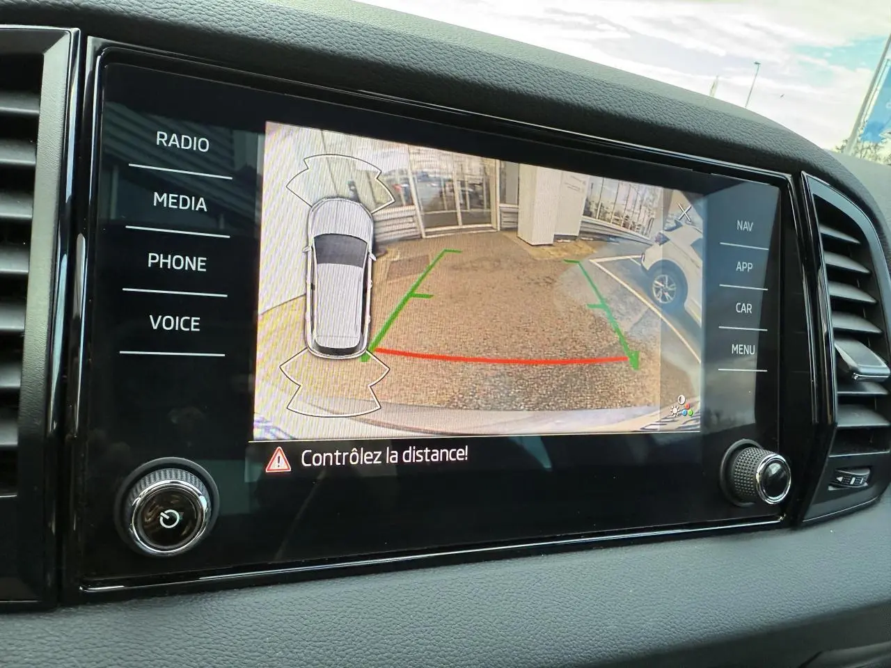 Écran tactile intérieur du Skoda Karoq 2023 montrant la caméra de recul avec guidage de stationnement actif.