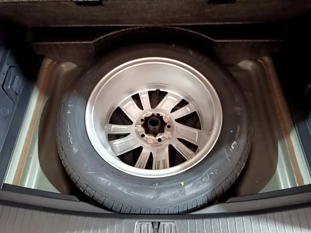 Roue de secours en jante aluminium dans le coffre du Volkswagen Touran gris foncé 2023, vue de dessus.