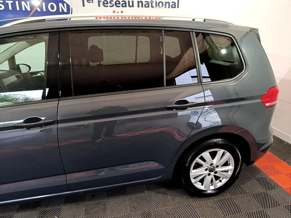 Profil côté droit du Volkswagen Touran gris foncé 2023 avec jante aluminium et vitres teintées.